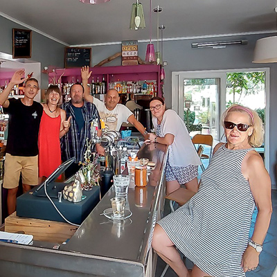 Groupe de personnes souriantes au comptoir du bar du camping